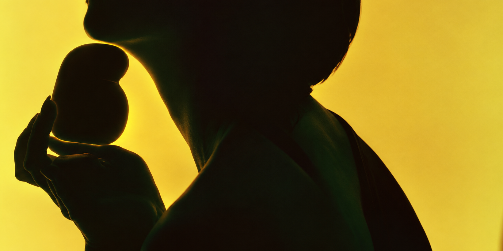 Silhouette holding the Bewdy Guru Device against yellow light