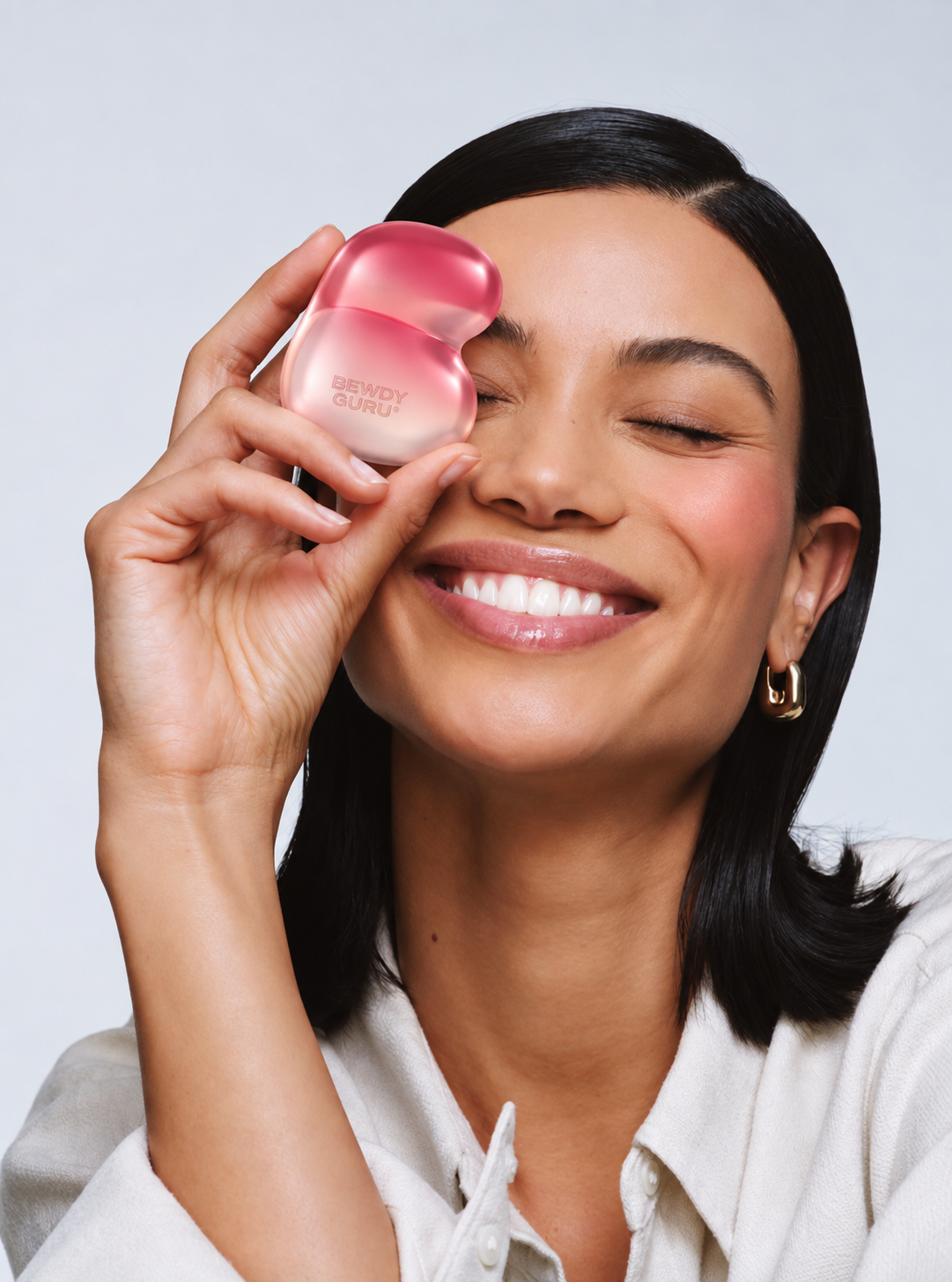Smiling woman holding the Bewdy Guru device to her cheek